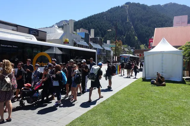 A yellow Orbus bus stopped in Queenstown, with passengers at the doors.