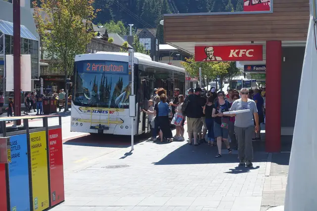 A yellow Orbus bus waiting at a Queenstown bus stop.