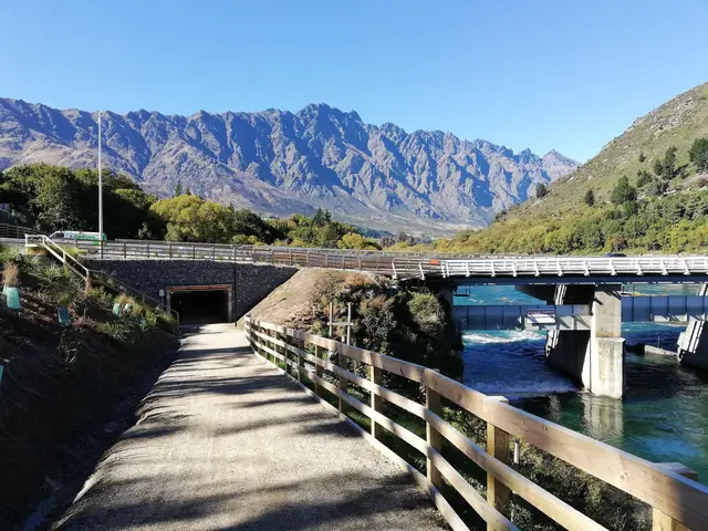 The Queenstown Trail passing the old Kawarau Falls bridge and the newer State Highway 6 bridge, with the Remarkables behind.
