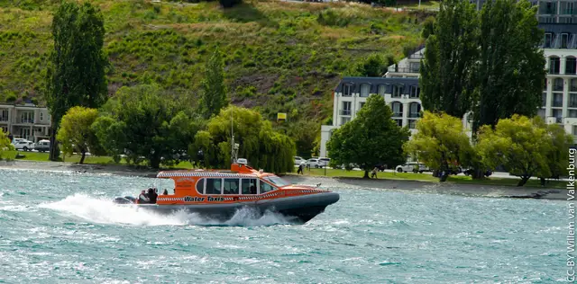 A water taxi moving across Lake Wakatipu in Queenstown Bay.