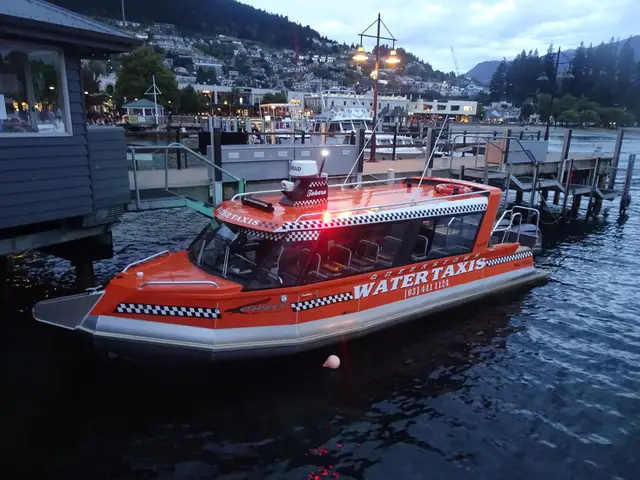 A white water taxi tied at the Queenstown Bay wharf, with the lake and the Remarkables behind it.